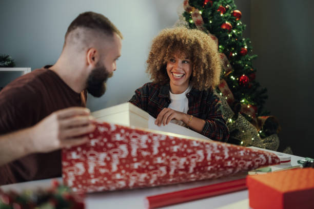 istock Couple wrapping christmas presents having fun together at home 2179733752
