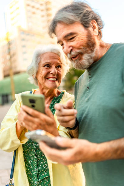 istock Senior couple walking using mobile phone in the city 2179735728