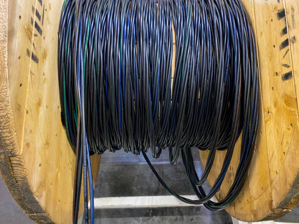 A spool of various wires is currently resting on a sturdy wooden spool, creating an interesting visual contrast between the materials and showcasing their respective functionalities