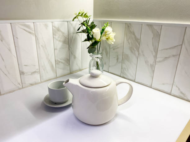 istock An Elegant White Teapot accompanied by a Cup and Fresh Flowers creatively arranged in a Modern Kitchen Setting, showcasing a blend of style and comfort 2179739363