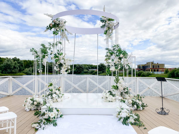 istock A stunning wedding arch adorned with white flowers and lush greenery stands on a charming deck, providing a perfect backdrop for the joyful celebration of love and unity 2179739409