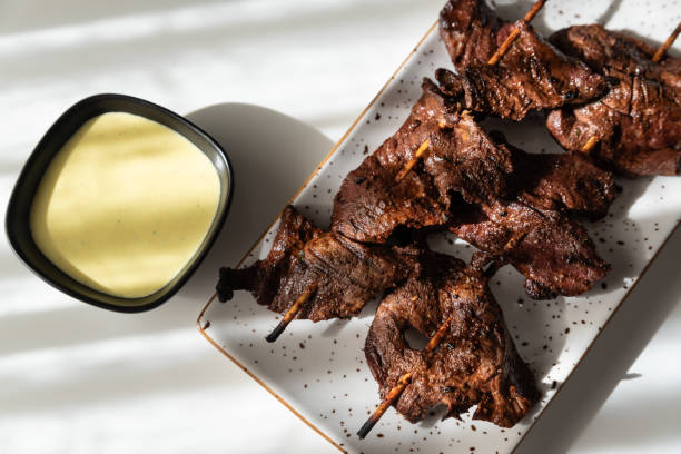 Freshly grilled Peruvian anticuchos served with hot sauce.