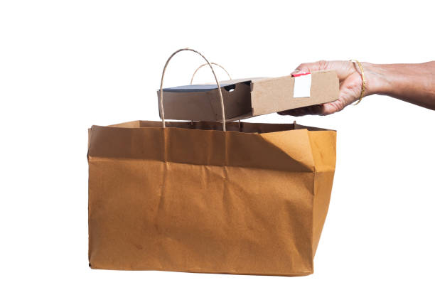 istock Indian woman's hand taking out pizza box from brown paper bag on white background. 2179740984