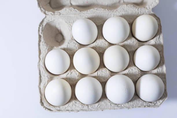 Closeup of White eggs in a carton box on a white background. Top view.