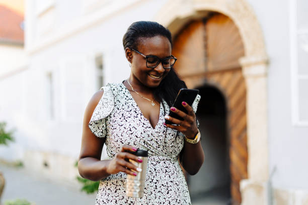 istock Smiling woman using phone on the street 2179755360