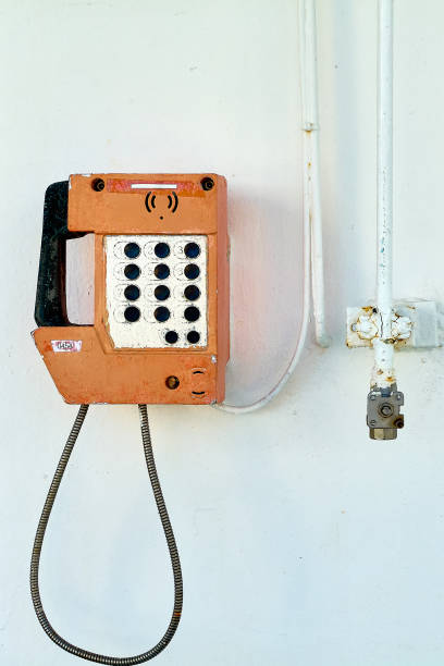 istock Worn orange telephone on a white background next to a pipe 2179760883