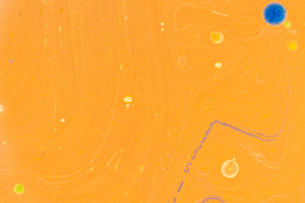 This image displays an abstract pattern with a predominantly yellow background. Swirls and dots of various colors, including blue, orange, and green, create a fluid-like appearance with a marbled effect. The vibrant colors and organic patterns make this background ideal for artistic and design projects.