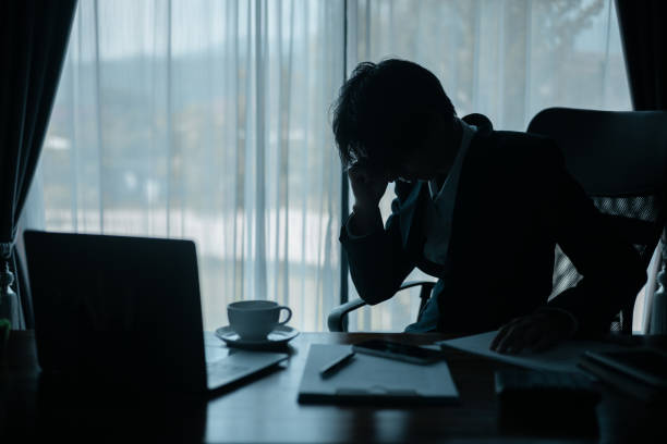 Emotional businessman laughing till one cries and rubbing eye in office; emotional stress