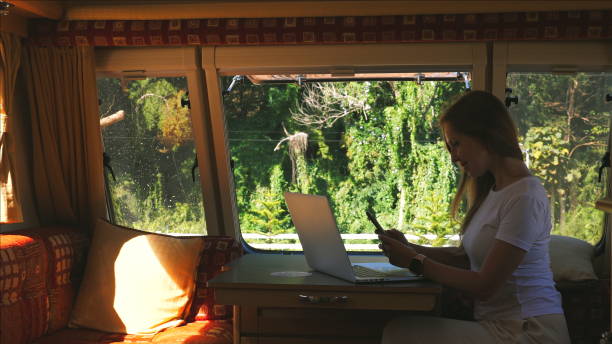 istock Young woman working remotely on laptop inside cozy camper van, 2179766092