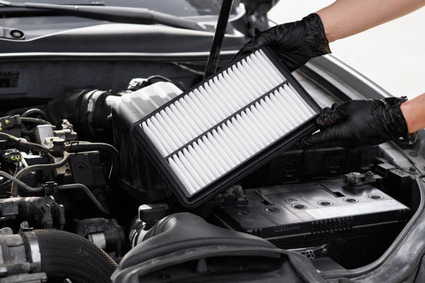 istock Car mechanic holds car air filter in hands near engine compartment, plans to replace old filter, close-up. Concept replacing auto parts, car maintenance, protection from allergens, dirt, soot 2179775473