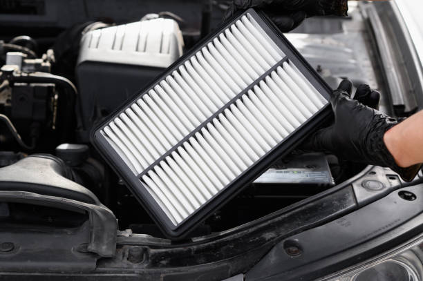 istock Auto mechanic holds car air filter in his hands near engine compartment, close-up. Concept of replacing auto parts, replacing air filter, car maintenance, protection from allergens, dirt,soot,viruses. 2179775574