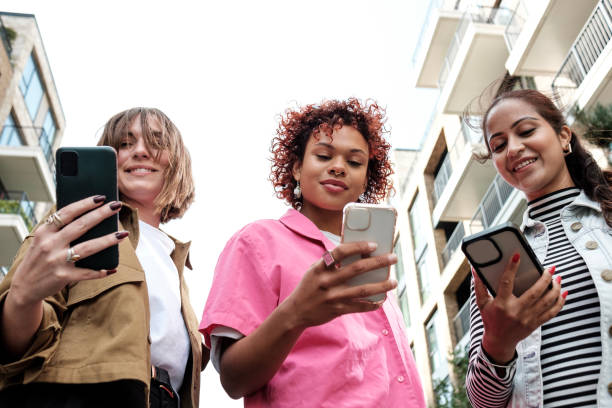 istock Three young women are using mobile phones while walking in the city 2179786915