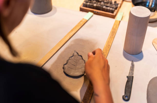 istock An artisan carefully shapes a ceramic leaf in a workshop, showcasing creativity and attention to detail. 2179793177