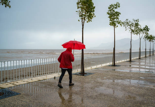 istock Lonely man walking on the beach on a rainy day 2179803784