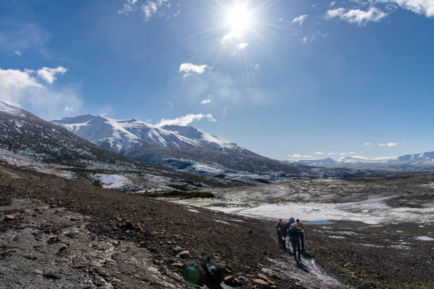 Torres del Paine National Park, Patagonia, Chile-April 8, 2024; hikers on central sector W-trek snow covered hiking route with snow covered mountains of the Paine Massif and bright sun in sky