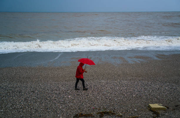 istock Lonely man walking on the beach on a rainy day 2179816352