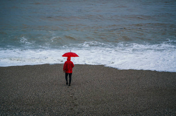 istock Lonely man walking on the beach on a rainy day 2179816477