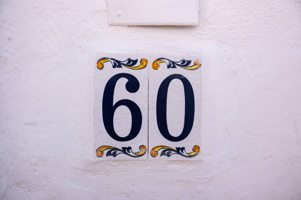 istock Beautiful house number 60 in Spanish style. House number on a ceramic patterned base in the old town in Spain. Traditional Spanish patterned decoration of a plate with an apartment or house number 2179817417