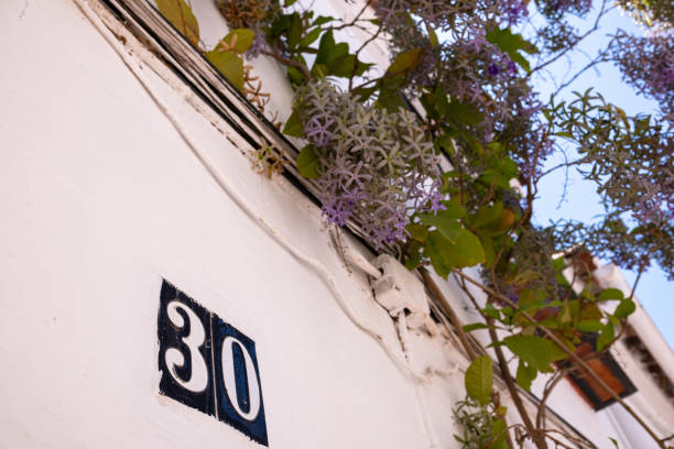 Beautiful house number 30 in Spanish style. House number on a ceramic patterned base in the old town in Spain. Traditional Spanish patterned decoration of a plate with an apartment or house number.