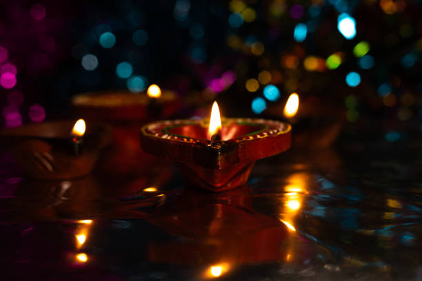 istock Glowing Diwali diyas with beautiful light reflection on the ground with bokeh effect in dark background. 2179825356