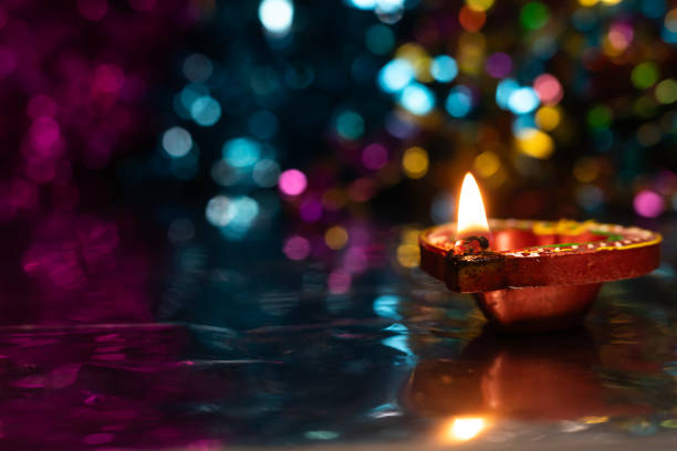 istock Glowing Diwali diyas with beautiful light reflection on the ground with bokeh effect in dark background. 2179825521
