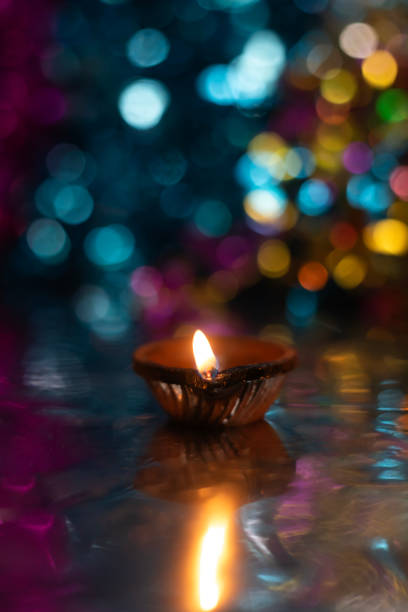 istock Glowing Diwali diyas with beautiful light reflection on the ground with bokeh effect in dark background. 2179825550