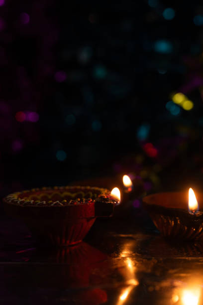 istock Glowing Diwali diyas with beautiful light reflection on the ground with bokeh effect in dark background. 2179825622