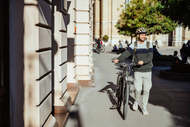 istock A man rides a bicycle through a historic European square surrounded by classical architectur. Cyclist with protective helmet commuting from work 2179826413