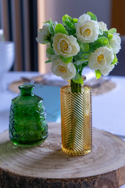 A wedding centerpiece featuring a glass vase with plastic flowers.