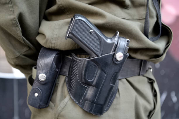 Holster with handgun and magazine case are on the belt of a serviceman