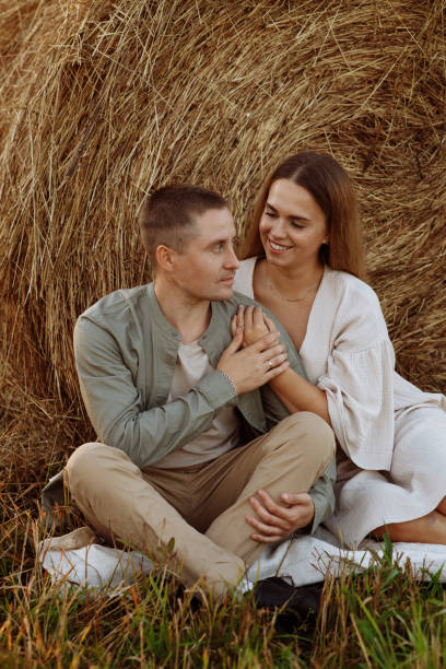 istock A couple is sitting on the grass next to a hay bale 2179827936