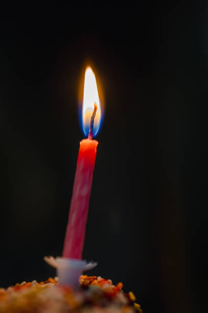 Red candle light Christmas candlelight on glowing flame sparkling green background blurred