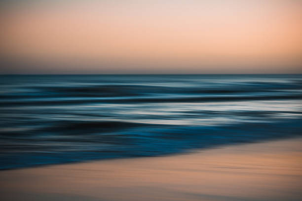 istock Blurred ocean waves under a soft orange and blue sky at dusk. 2179830972