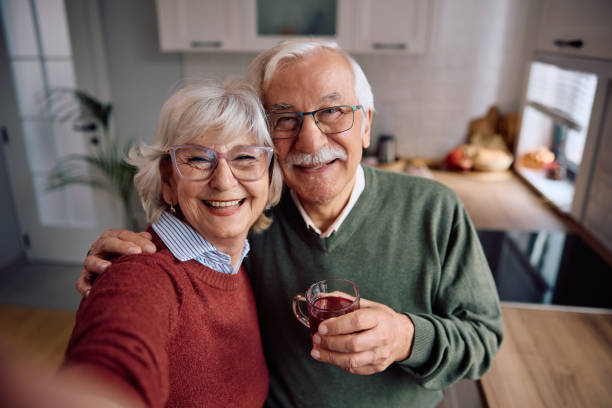 Happy senior couple taking selfie and looking at camera.