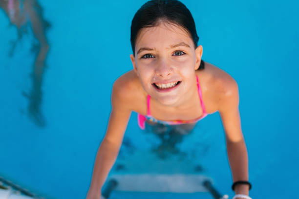 Beautiful toddler child, blond boy, swimming in a pool in backyard on sunset