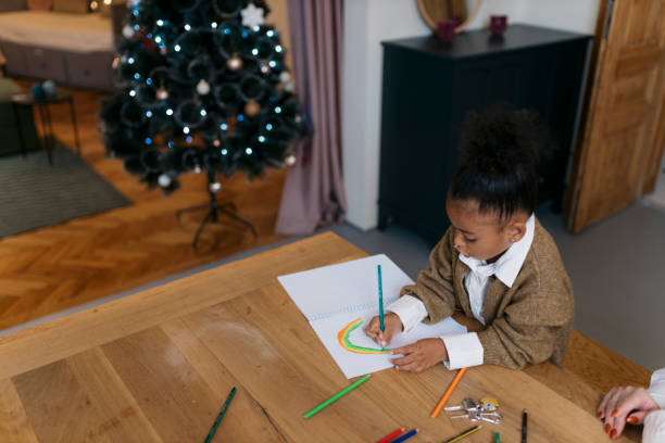 istock Small girl making a drawing sitting at table at home during Christmas 2179845646