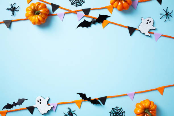 istock Frame of Halloween decorations, pumpkins, bats, ghosts, and spiders on a light blue background. Flat lay, top view, copy space. 2179847689