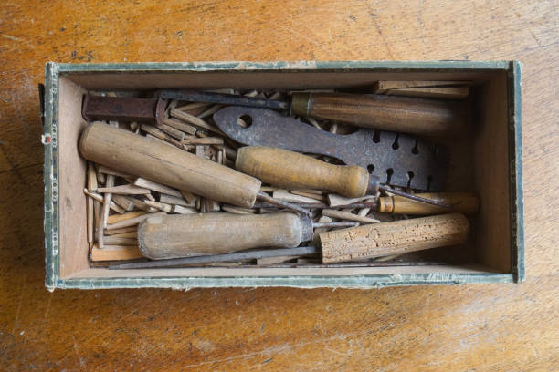 This old box with small tools and handmade wooden pins belonged to a chair maker, the pins have been used for keeping the wicker cane in place while weaving the seat of the chair with Viennese braid or wickerwork. View directly from above.