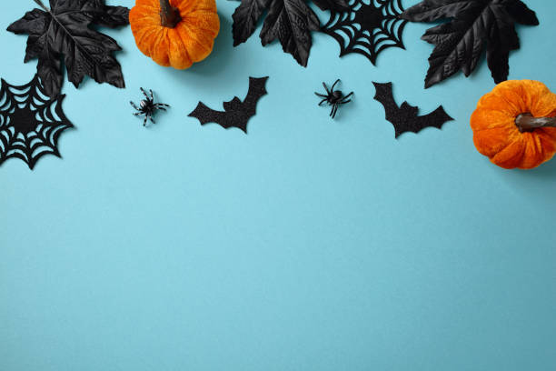 istock Flat lay spooky Halloween decorations, pumpkins, black leaves, and spider webs on a blue background 2179848033