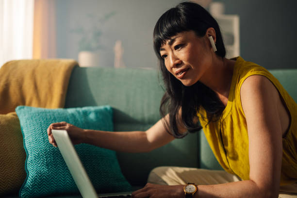 istock Asian woman adjusting her laptop while seated on a green couch. 2179849009