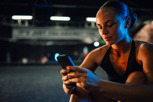 istock Focused female athlete using smartphone at the gym after evening workout 2179850139