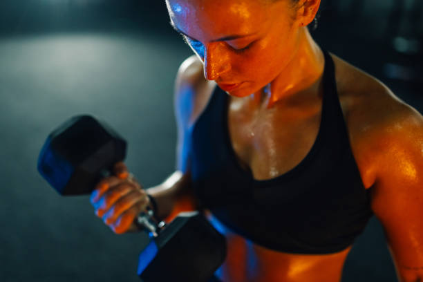 istock Sportswoman lifting dumbbell and training biceps in gym 2179850143