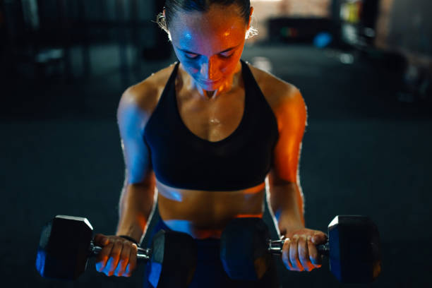 istock Sportswoman lifting heavy dumbbells during intense workout session 2179850168