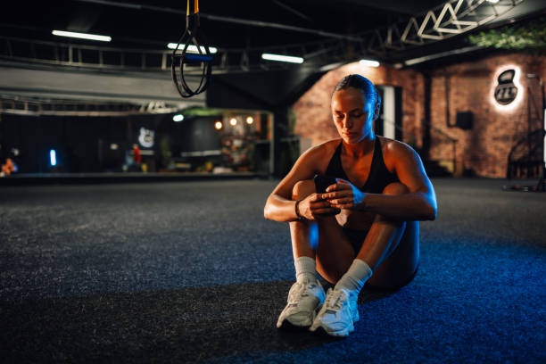 istock Young athletic woman using smartphone app after training in gym 2179850175