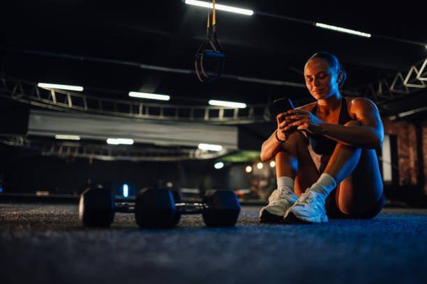 istock Young athletic woman using smartphone app in gym after training session 2179850193