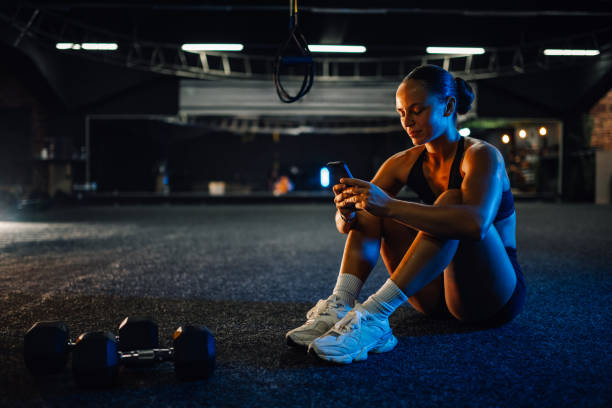 Sporty woman using smartphone after training session in gym