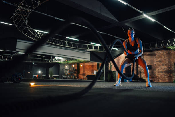 istock Determined sportswoman doing exercise with battle ropes during cross training workout 2179850207
