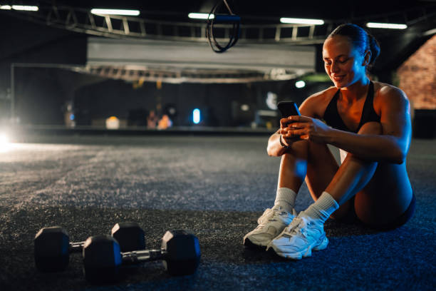 istock Young athletic woman using smartphone app after training in gym 2179850216