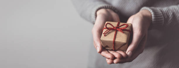 Hands holding little gift with red bow. Close up.