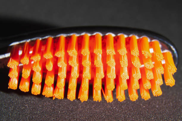 Black head toothbrush with orange bristles close up on black background